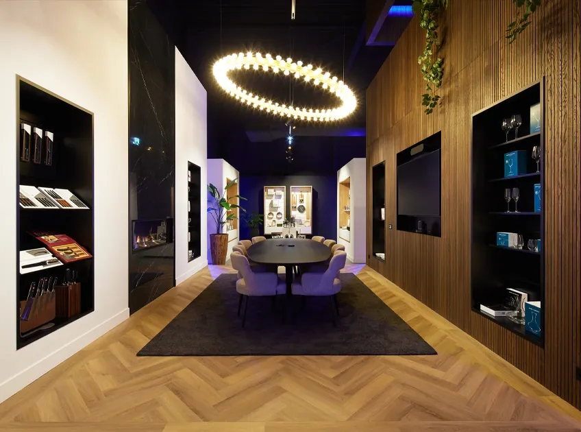 Showroom met glazen en messen uitgestald in open kasten en een vergadertafel met stoelen in het midden