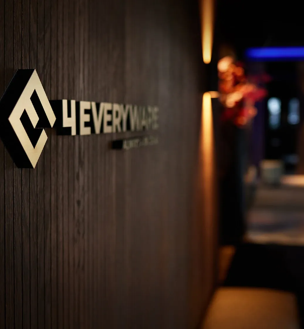 Bedrijfslogo van 4everyware op een houten wand in de showroom, stijlvol verlicht in moderne kantooromgeving
