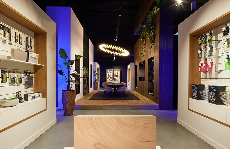 Showroom met glazen en messen uitgestald in open kasten en een vergadertafel met stoelen in het midden