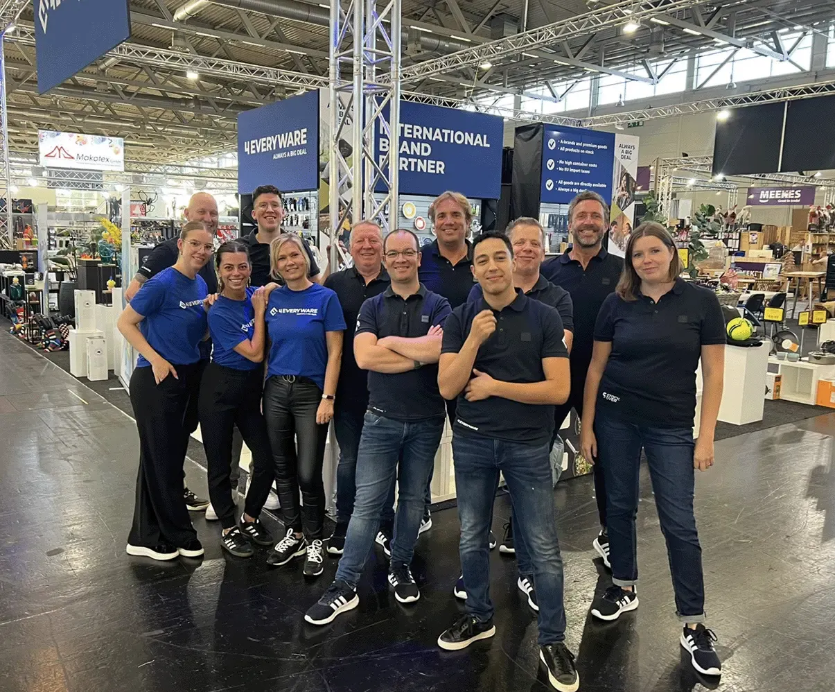 Team van 4everyware poseert samen op een internationale beursstand, klaar om klanten en partners te ontmoeten